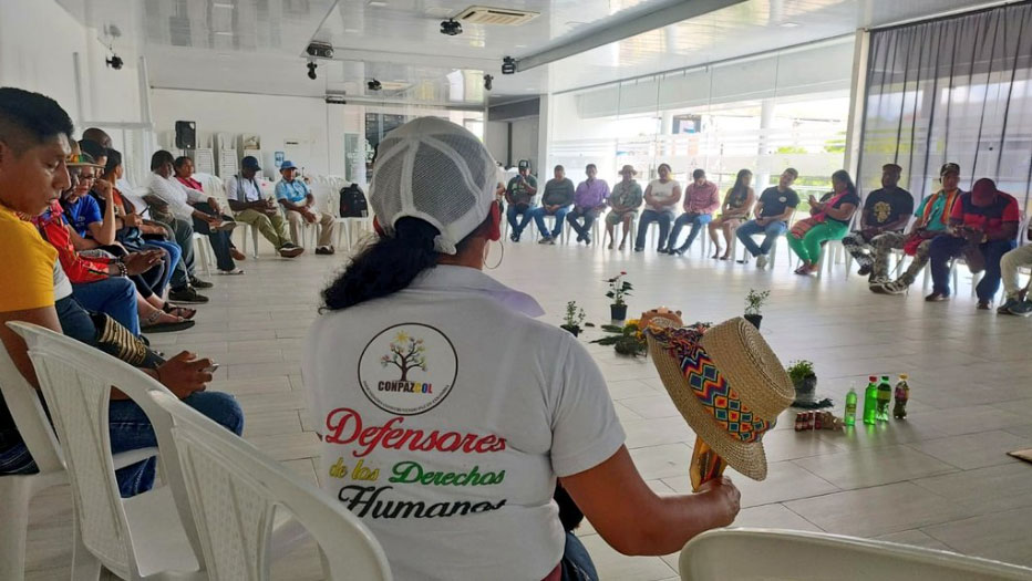 Gathering for Biodiversity and Peace in Putumayo, Colombia. A large room where people sit in chairs in a large circle facing each other. 