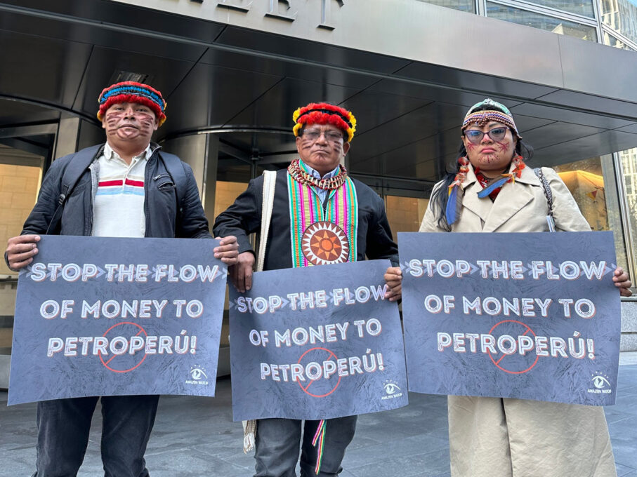 Activists from the MarAmazonia Aliiance hold signs saying Stop the flow of money to Petroperu